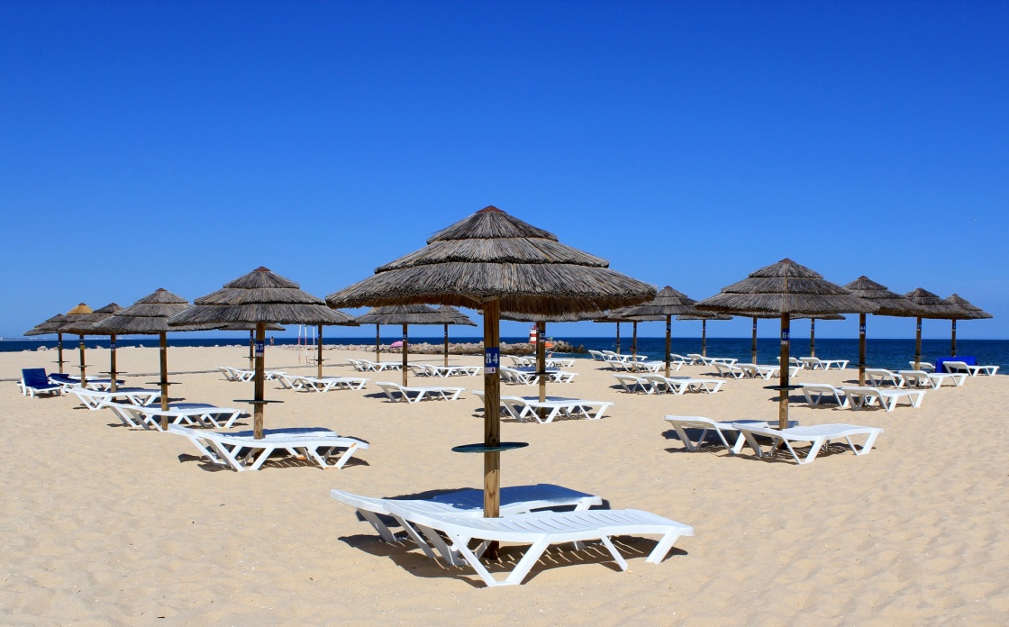 Parasol and sun loungers on the beach sand, Tavira island, Algarve. Portugal